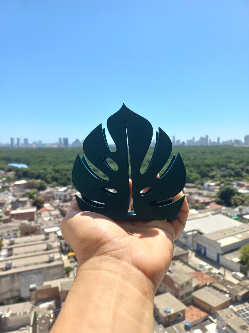 Porta-guardanapo verde em forma de folha de costela-de-adão, com a cidade ao fundo